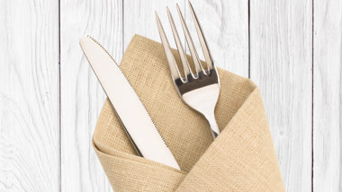 utensils in burlap napkin on white wood