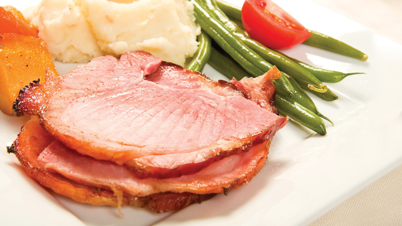 slices of ham with green beans, mashed potatoes and sweet potatoes